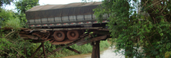 Caminhão carregado de laranja quebra ponte e quase cai em córrego